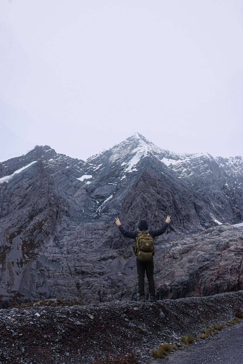 a man standing on a mountain with his arms outstretched
