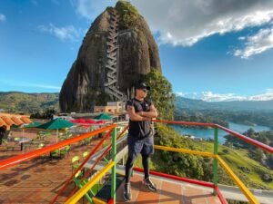 a man standing on top of a balcony next to a mountain