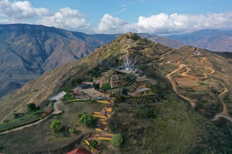 Hilltop monument with winding paths against a mountainous landscape