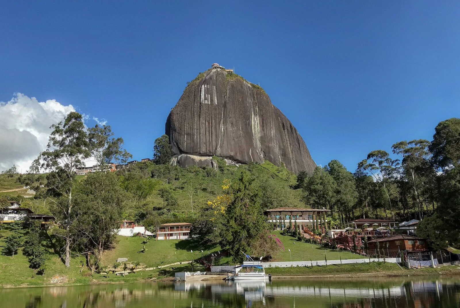 a large rock sitting on top of a lush green hillside